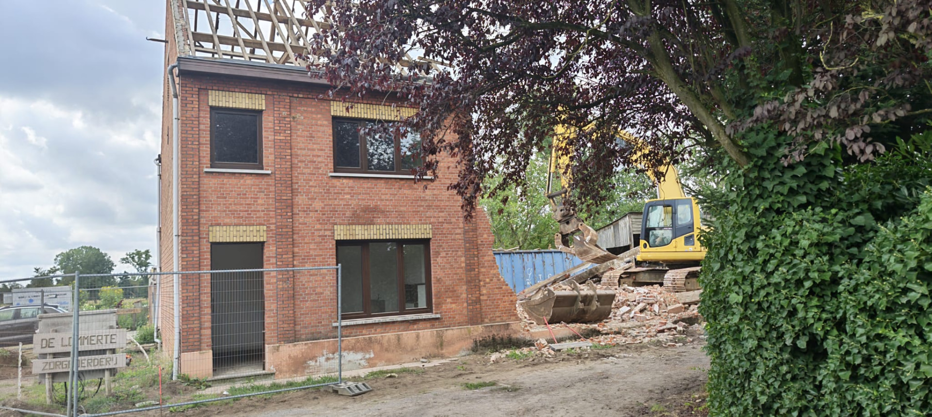 Afbraak van bakstenen woning met graafmachine en puin