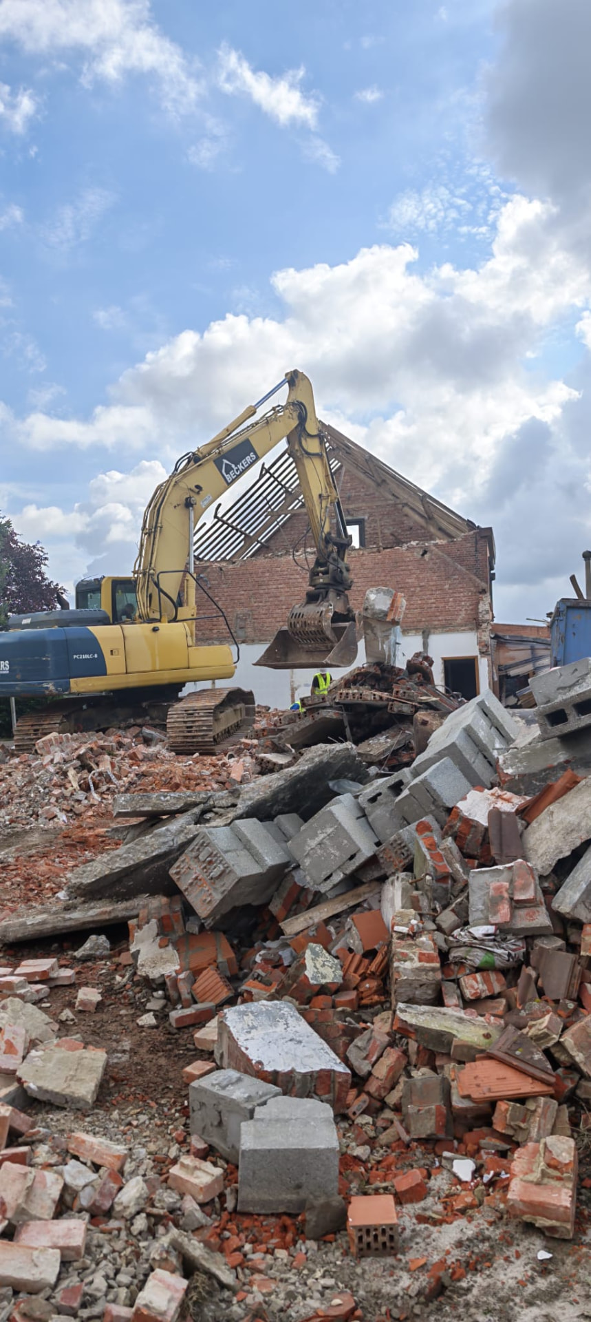 Graafmachine laadt puin en betonblokken op de werf